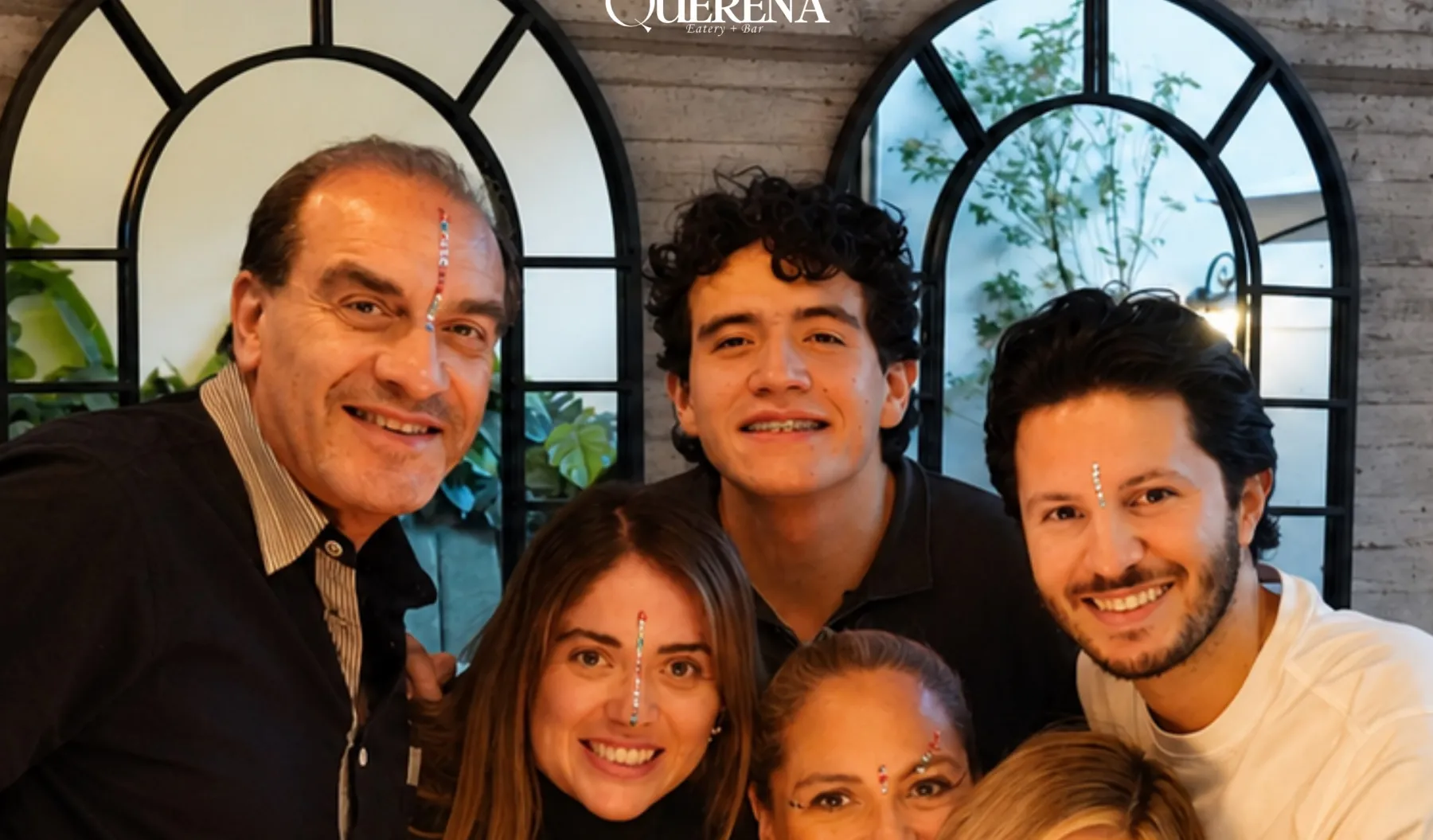 Una familia celebrando un cumpleaños en el salón de Querena, con el pastel encendido delante de los espejos de arco.
