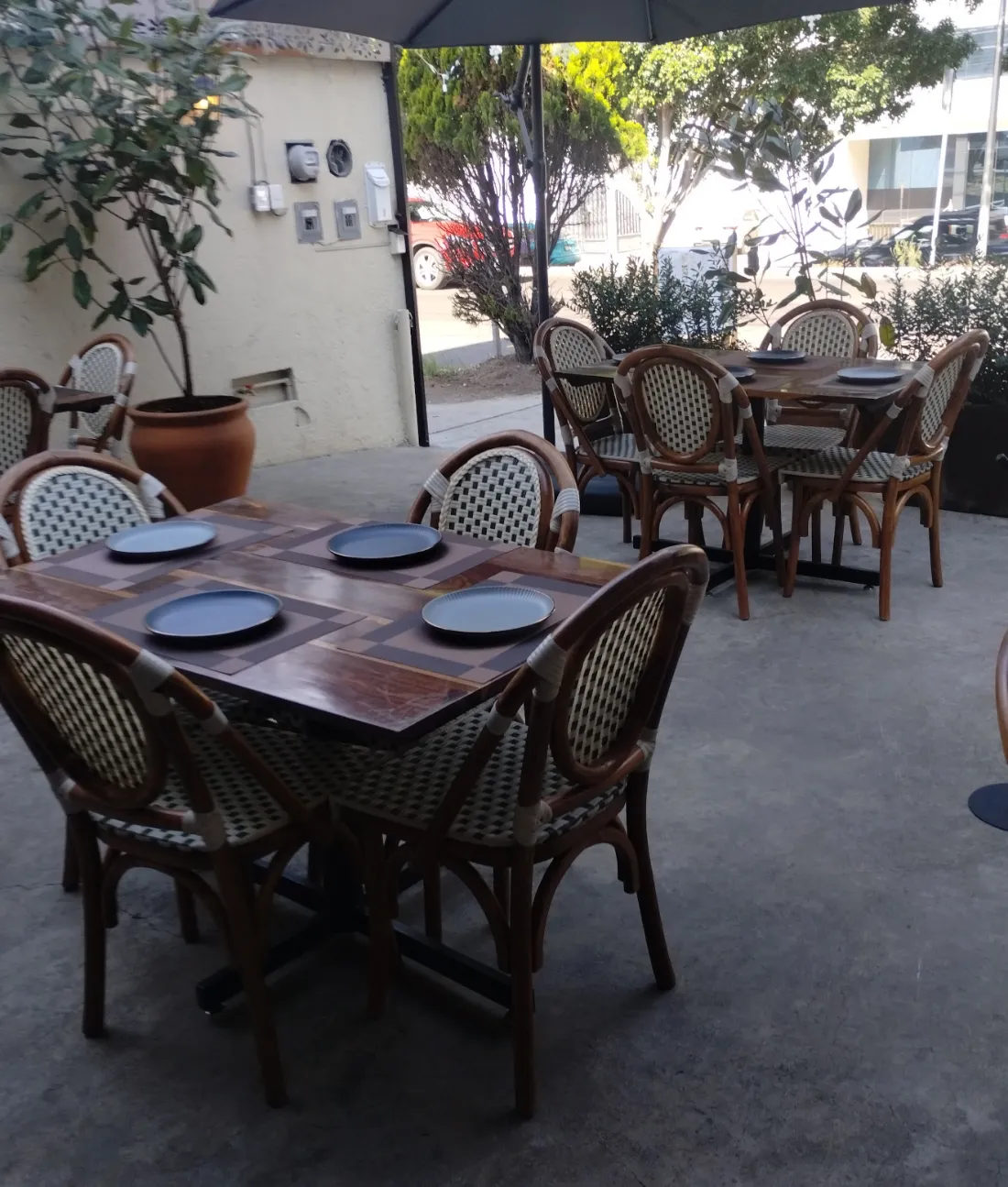 Las mesas de la terraza puestas por la mañana, con las sillas de bejuco y las macetas.