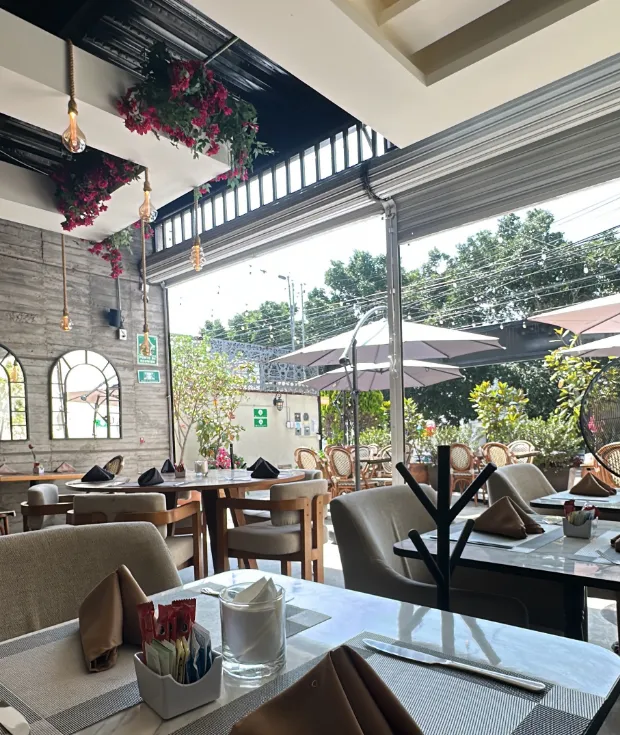 El comedor cubierto de Querena, con la bugambilia del techo y la terraza al fondo.