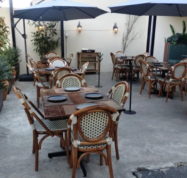 Las mesas de la terraza bajo las sombrillas, con las sillas de bejuco.