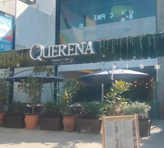 La fachada de Querena de día, con el letrero y las macetas de la entrada.