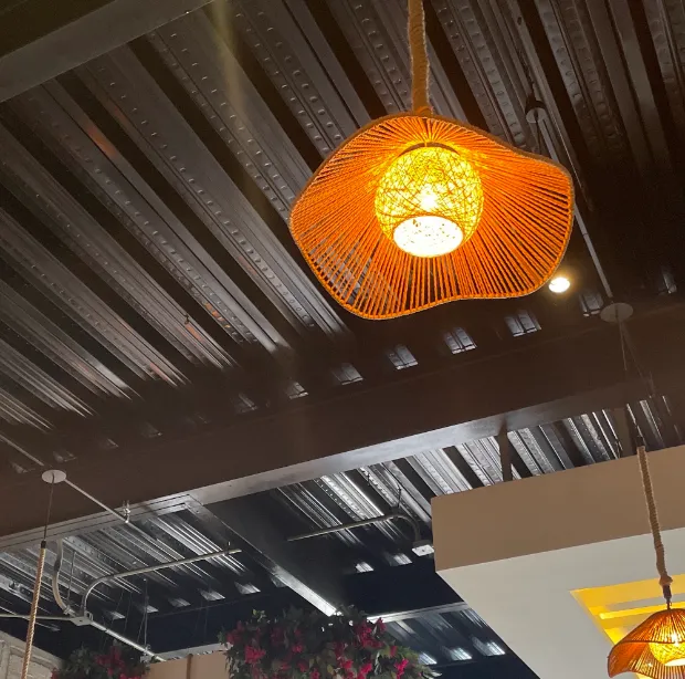 Una lámpara de fibra tejida colgando del techo negro del local.