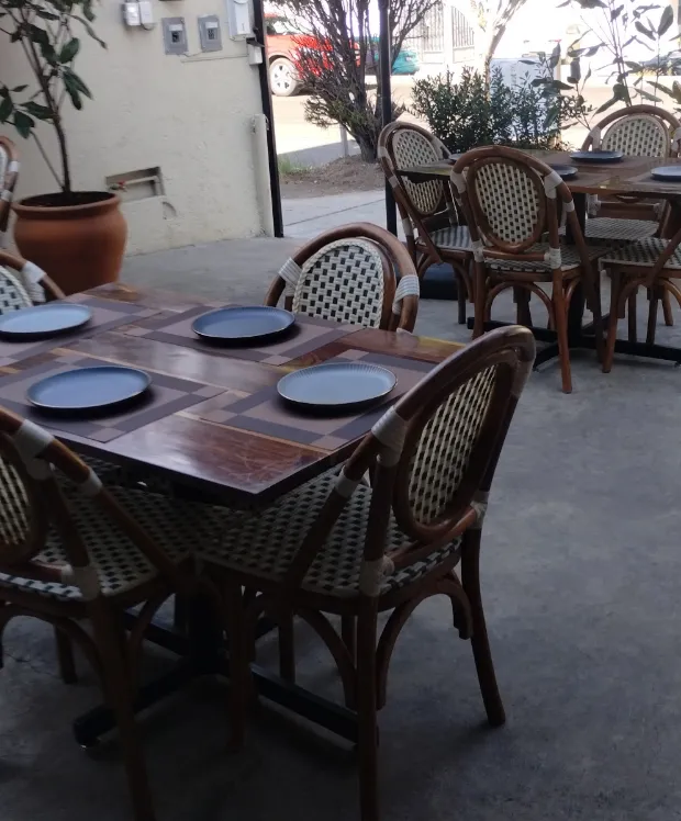 Una mesa de madera puesta con platos oscuros y servilletas dobladas.