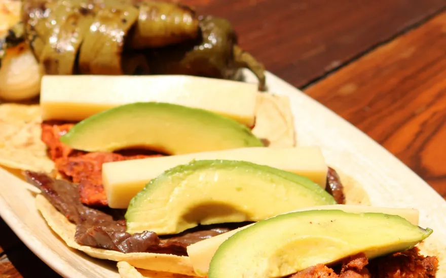 Tacos de cecina de Yecapixtla con nopal asado, láminas de aguacate y queso, en un plato ovalado.