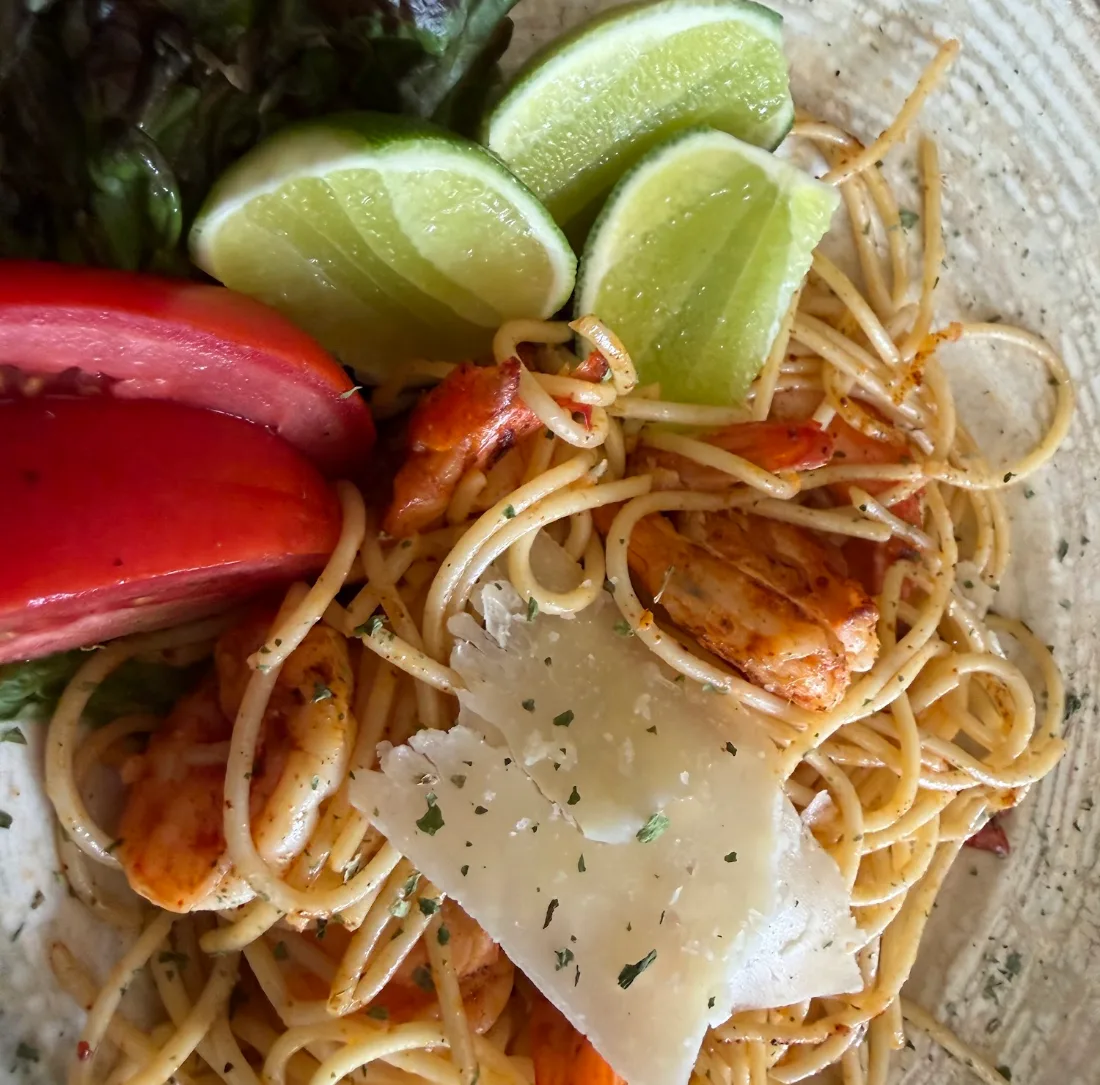 Pasta con camarones, láminas de parmesano, jitomate y limón.